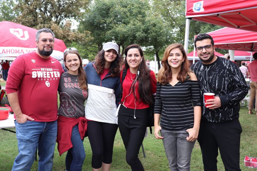 Group of 6 students, one holding a red solo cup, standing near o u tailgates