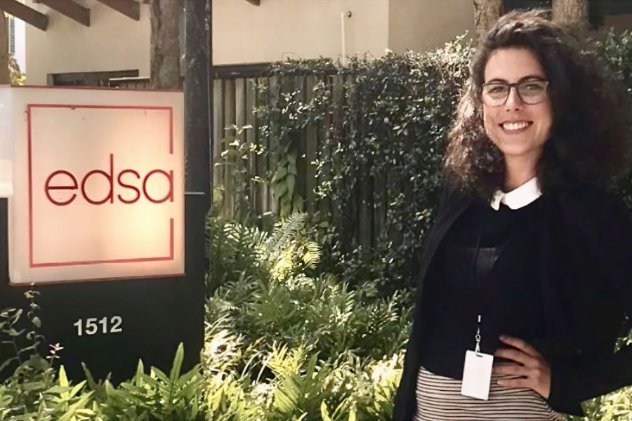 A photo of Alice Calmon standing in front of a sign that says e d s a