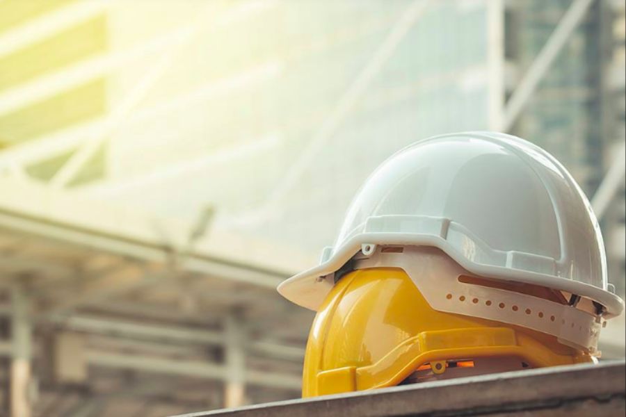 Two hard hats sitting on one another with a building under construction in the background stock photo