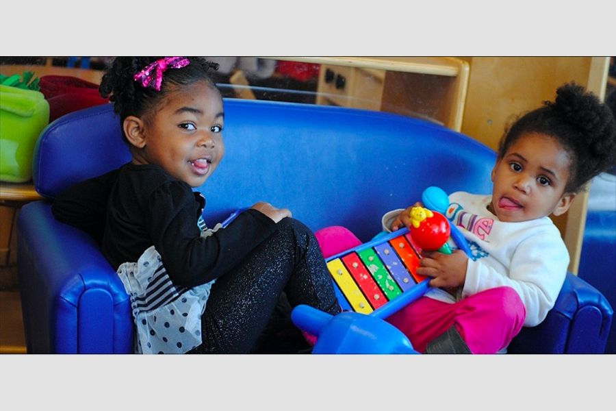 Two young children on a couch with toys.