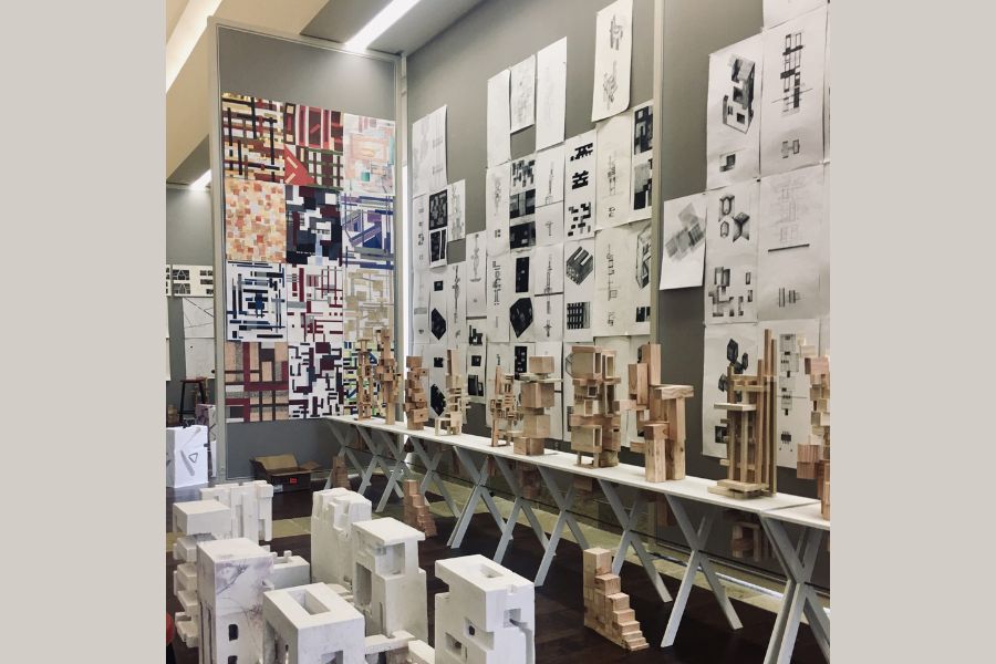 Architectural posters hanging on a wall and models standing in front