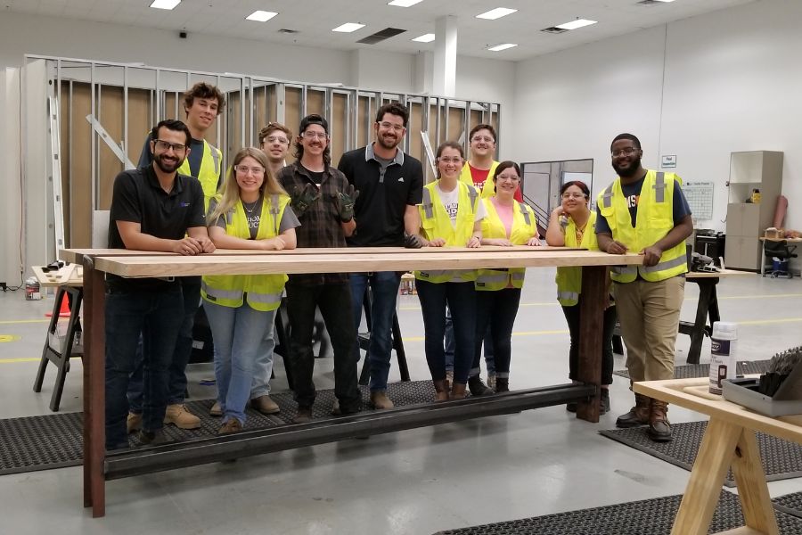 Students and others standing in a shop wearing PPE vests