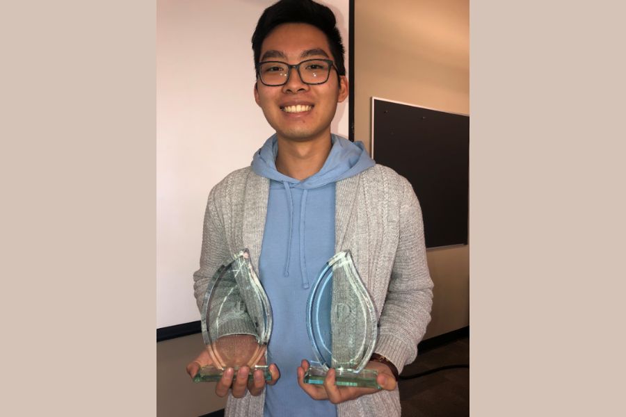 A photo of Henry Truong holding two trophies