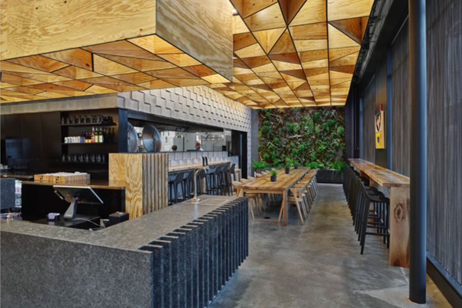 Restaurant interior with plywood coffered ceiling and long communal tables