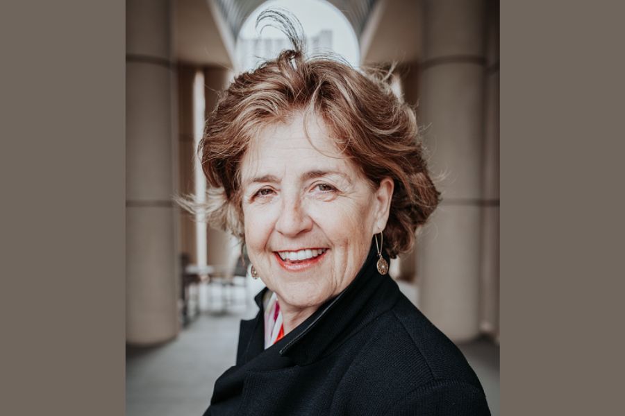 Smiling woman in black coat standing between columns