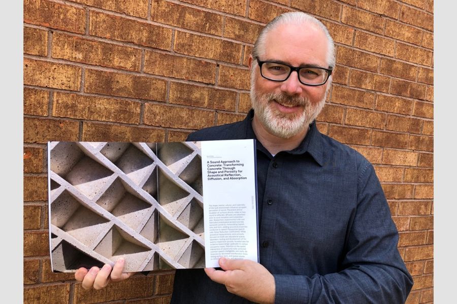 Daniel Butko with a book featuring his research on Acoustically Diffuse and Absorbent Lightweight Aerated Concrete.