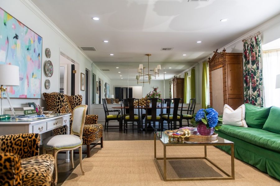 Living room with a green sofa, patterned chairs, and a dining table in the background.