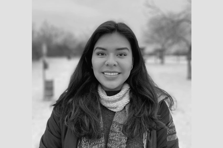 Black-and-white portrait of Viridiana Hernandez smiling outdoors in a park, wearing a scarf and jacket.