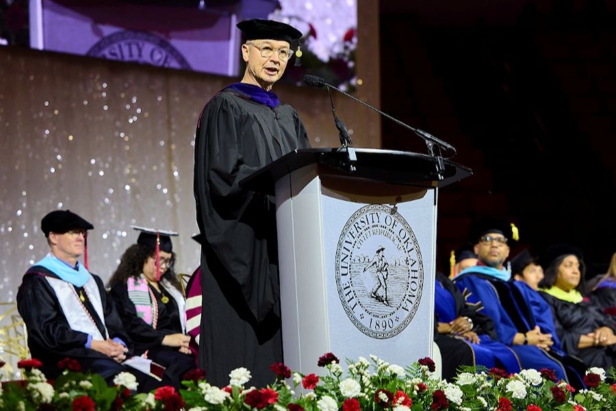 The dean of the college of architecture dressed in academic regalia speaking from a podium.
