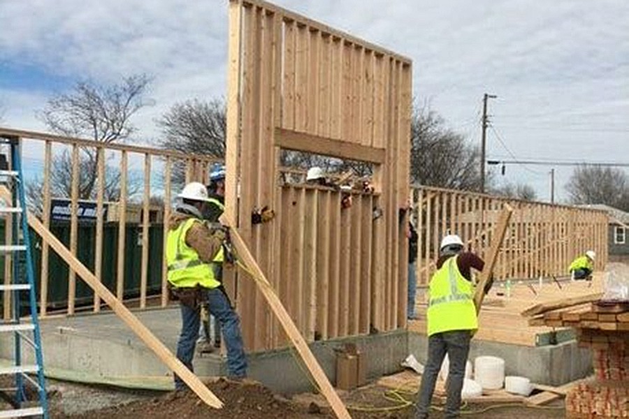 Construction works put up a wood housing frame outside.