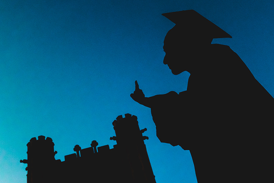 Silhouette of a graduate in their graduation cap and gown.