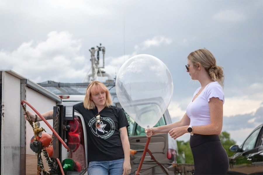 Two meteorology students blowing up a weather balloon.