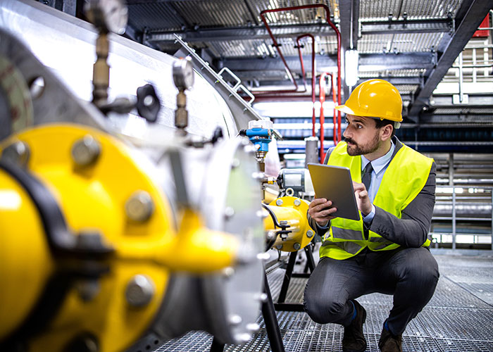 A person in safety gear checking a natural gas pipeline.