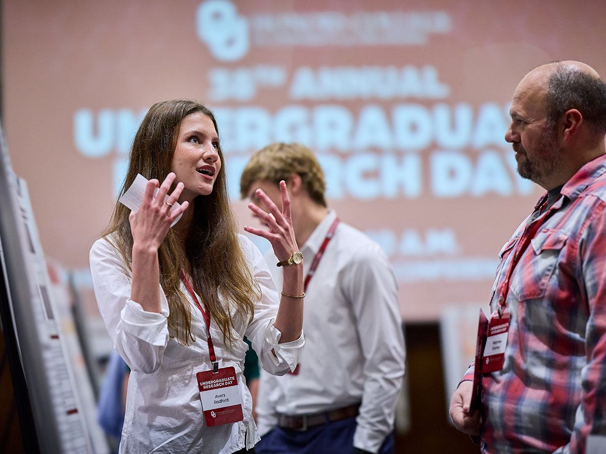 A students sharing ideas with a faculty member at a research event.