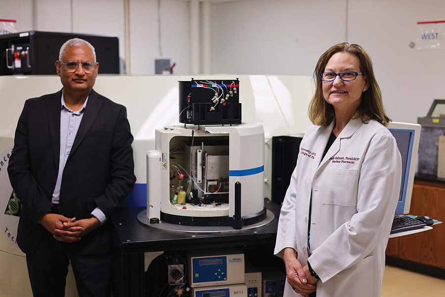 Two scientists in front of a cyclotron.