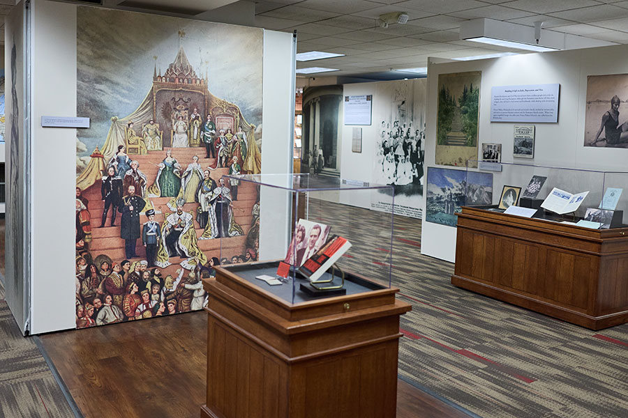 Two displays and walls in an exhibit showing artwork, photographs and literature.