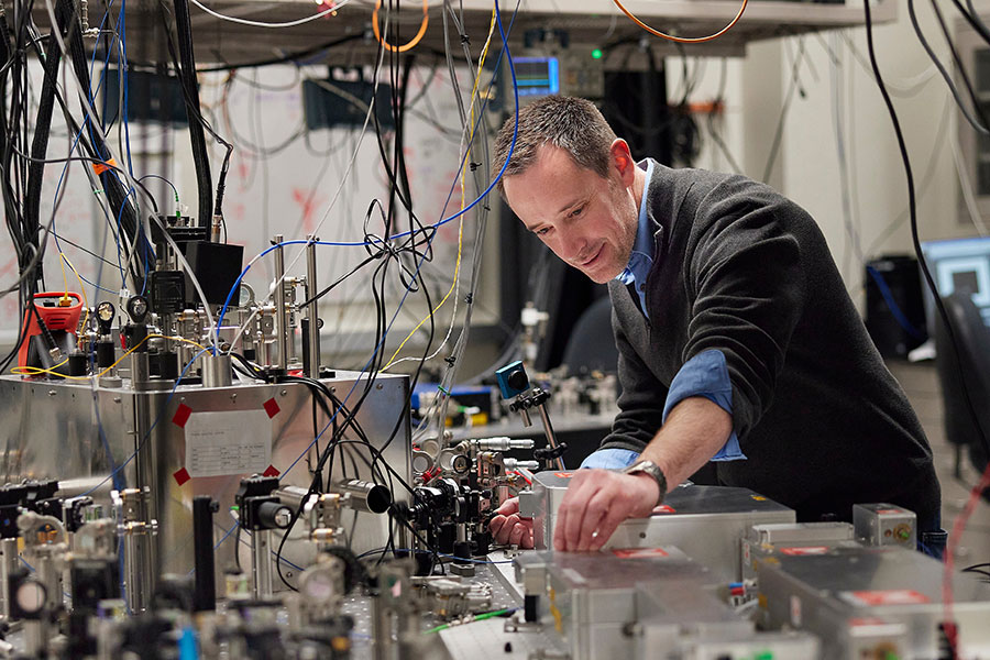A man bending over technology in a lab. 