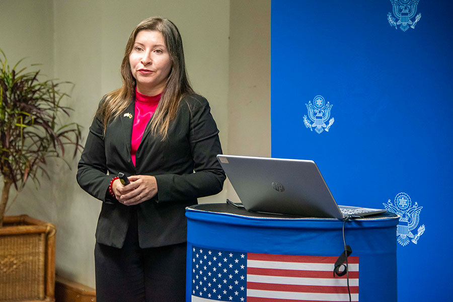 Jessica Cerezo-Román, Ph.D., stands next to a podium with an American flag during a presentation.