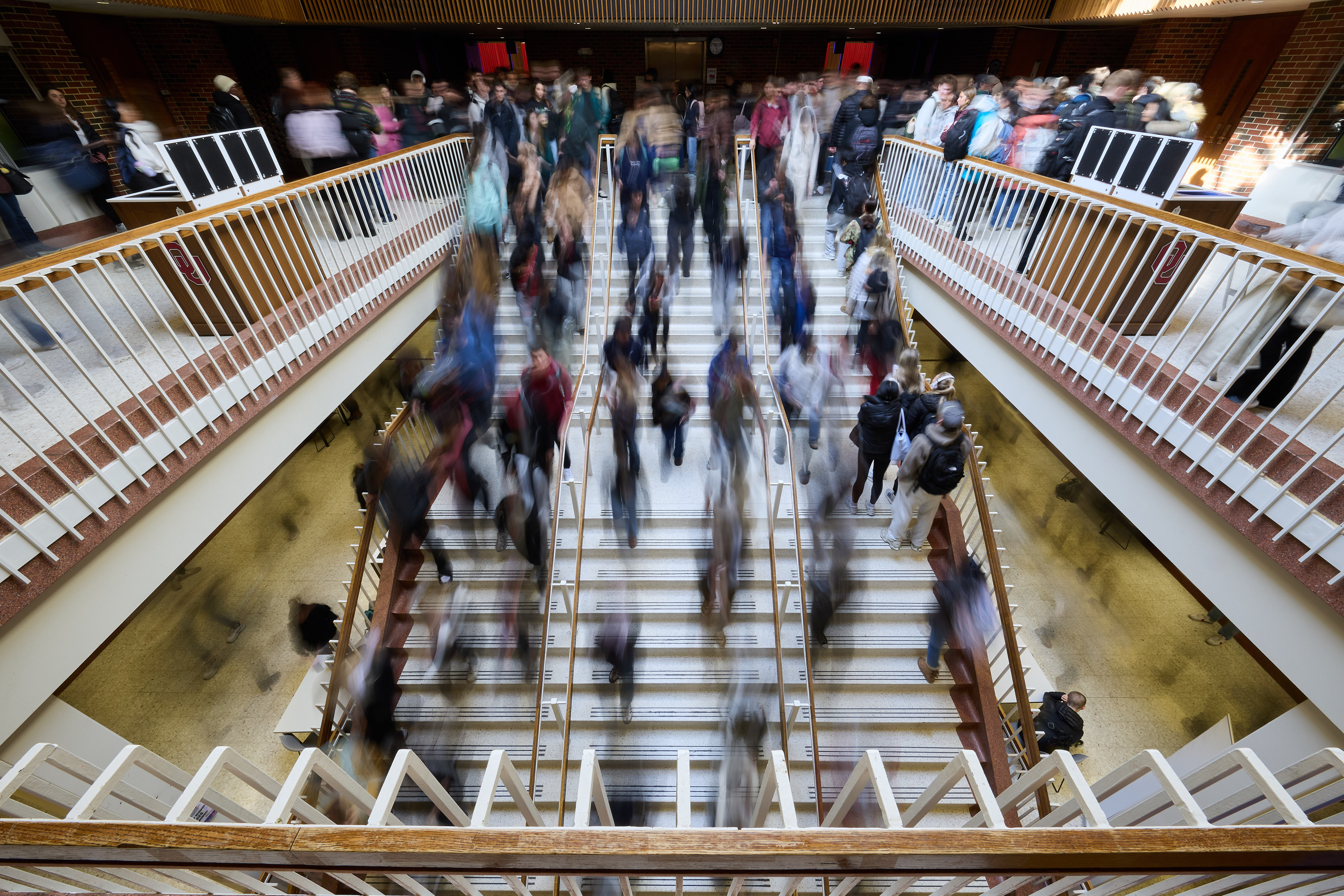 Students walking up stairs, taking in a blurred way to imply motion.