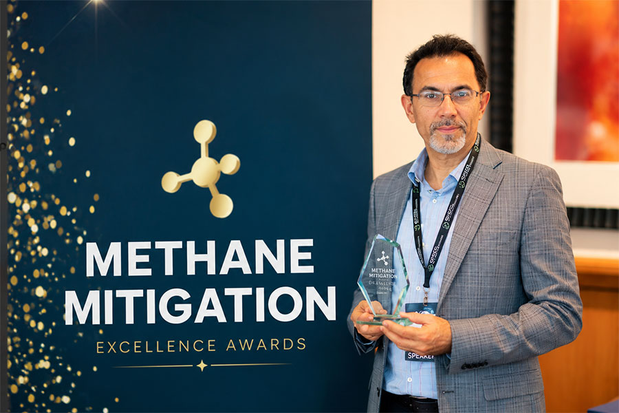 Pejman Kazempoor holds award while standing next to event banner for the Methane Mitigation Excellence Awards.