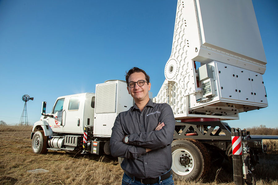 Man standing in front of a large radar attached to a truck.