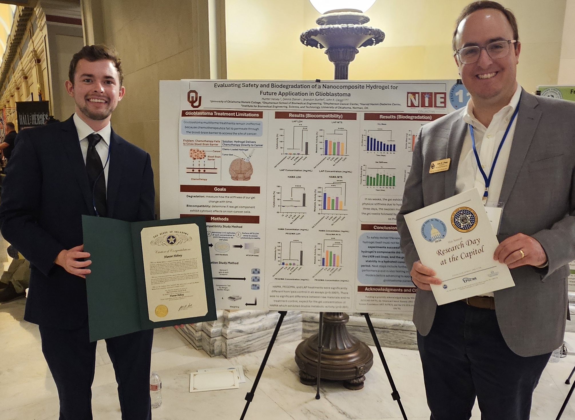 Two individuals stand in front of a scientific poster. 