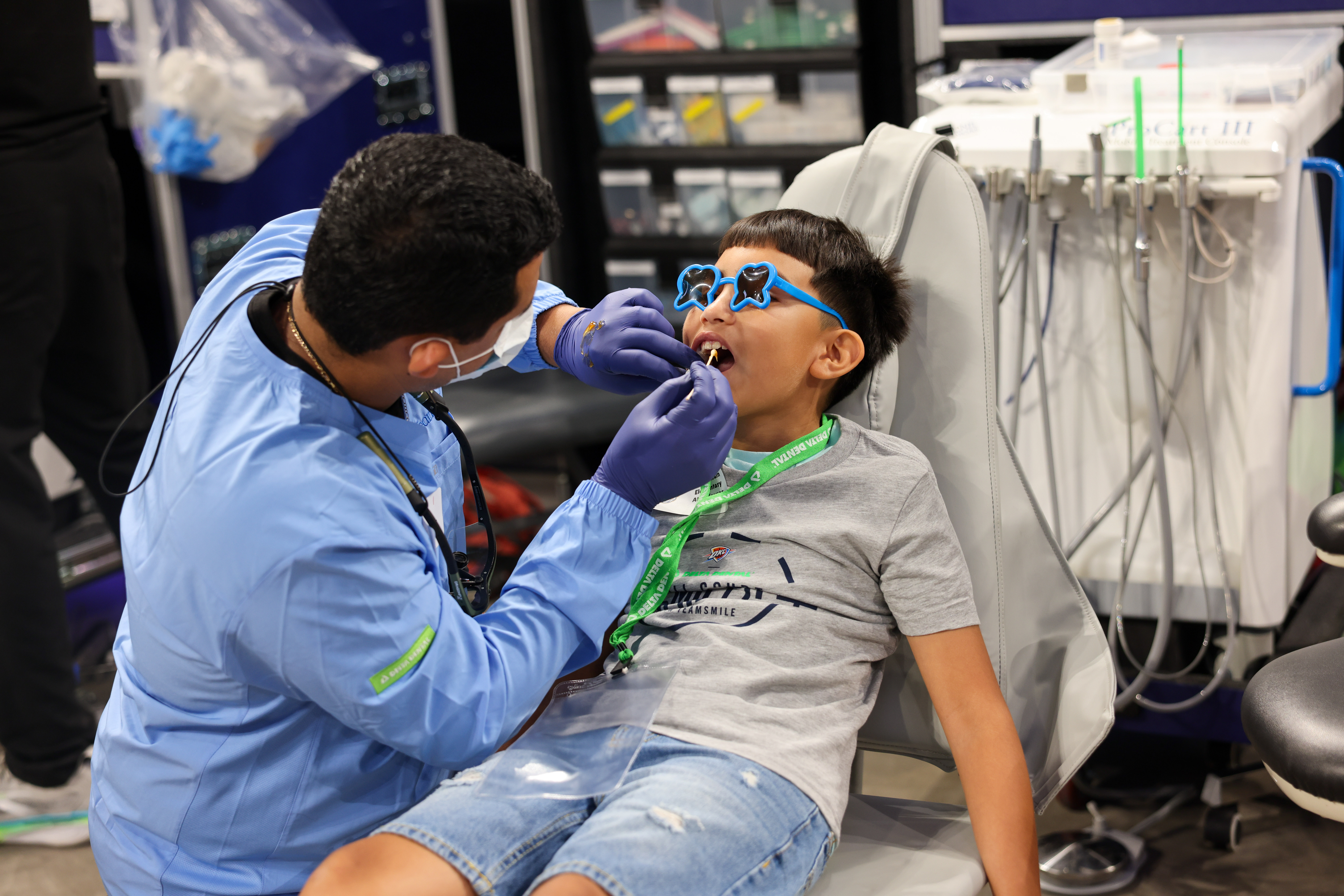 A dentist cleans the teeth of a young boy.