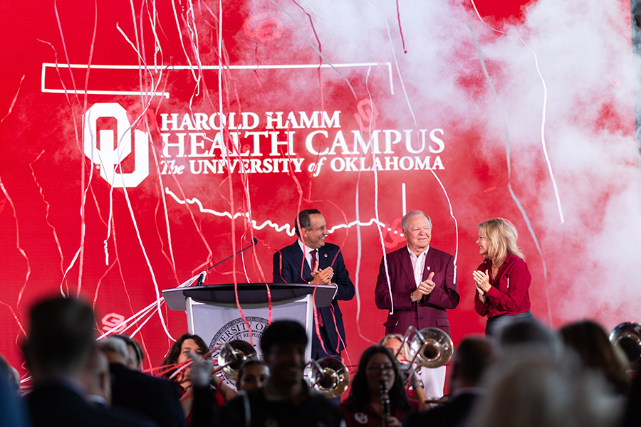 OU President Joseph Harroz Jr., Harold Hamm, and Shelly Lambertz standing on a stage.