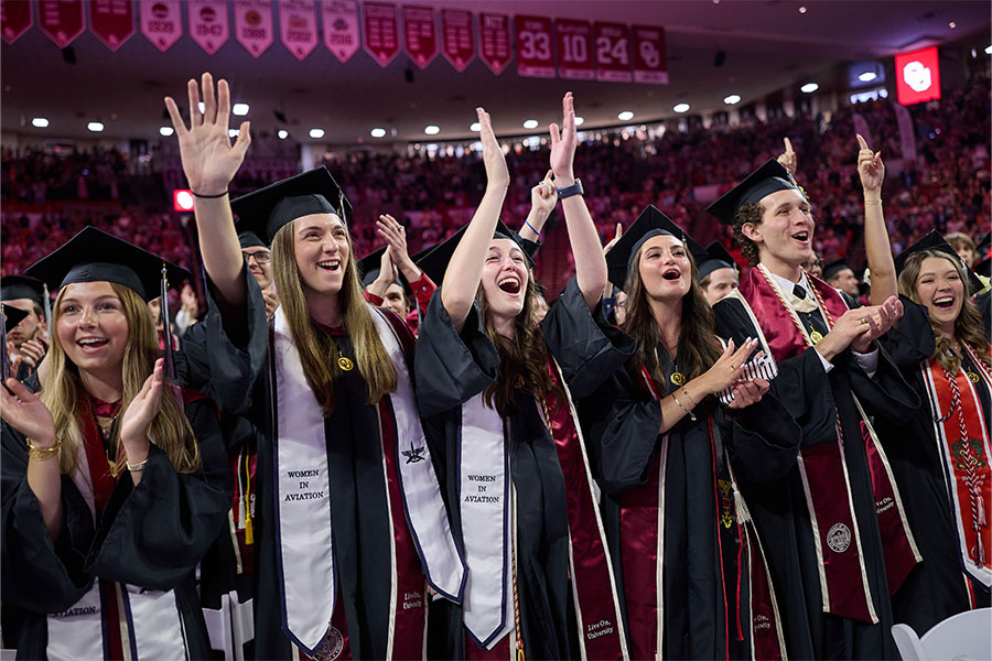 Students in graduation regalia celebrating at Lloyd Noble Center.