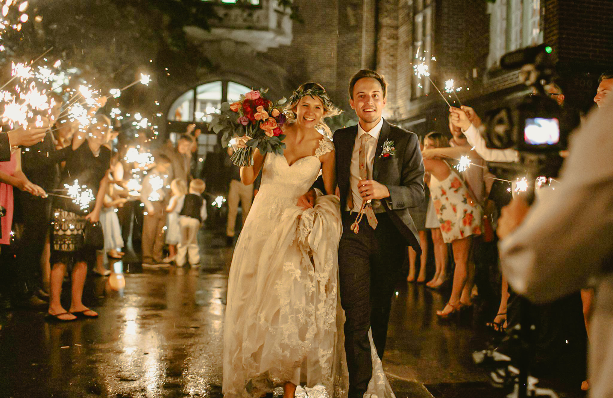 A bride and groom exiting the Oklahoma Memorial Union surrounding by people holding sparklers