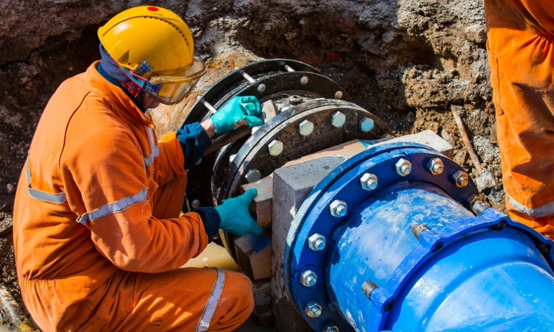 A person applying anti corrosion products on a pipeline