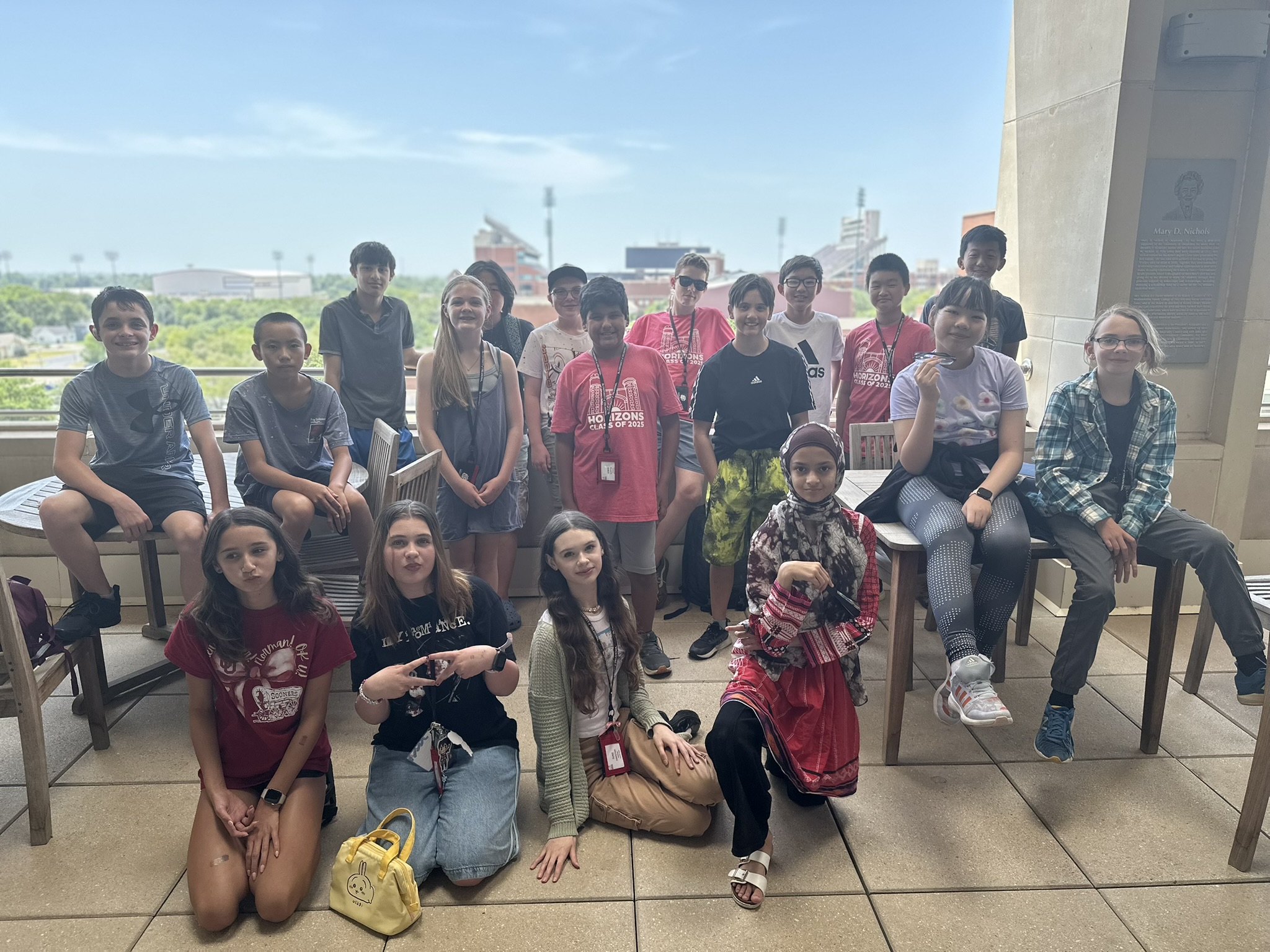 Students posing for a photo on the terrace with the stadium in the background. 