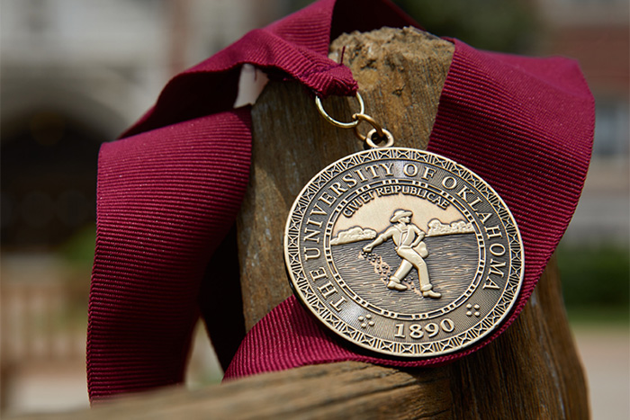 University medal draped over a bench corner.