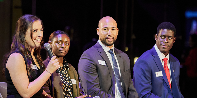 Several students sitting onstage during a speaking panel. 