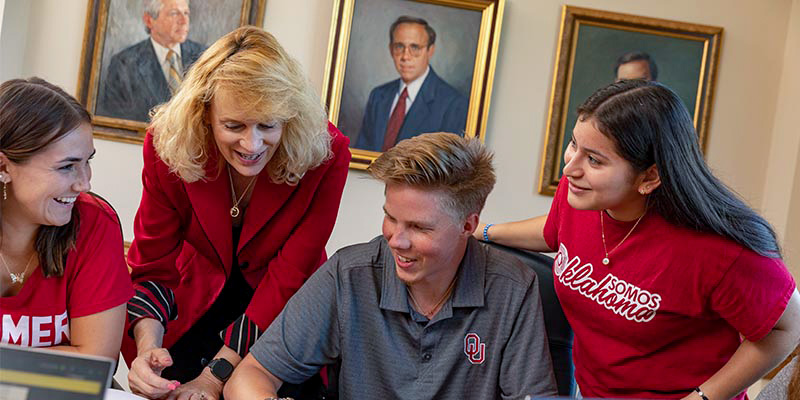 Professor helps asist a group of three students who are working together.