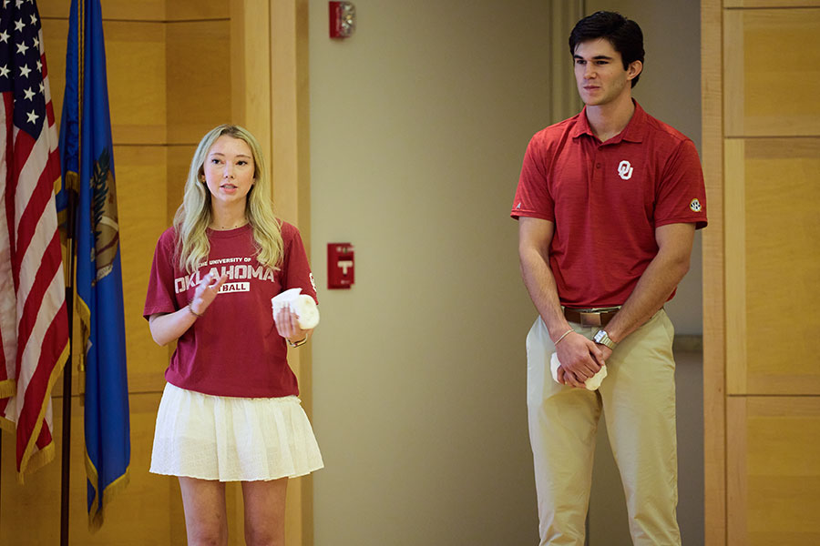 A male and female student stand on stage presenting their business idea for investors.