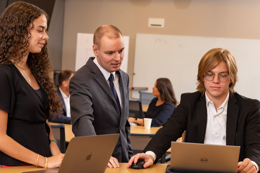 People standing and sitting around laptops.