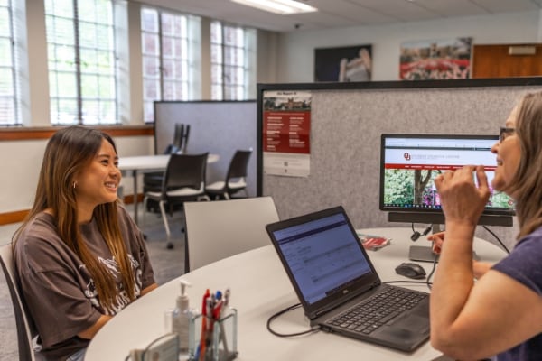 Two students sitting at a table with a laptop.