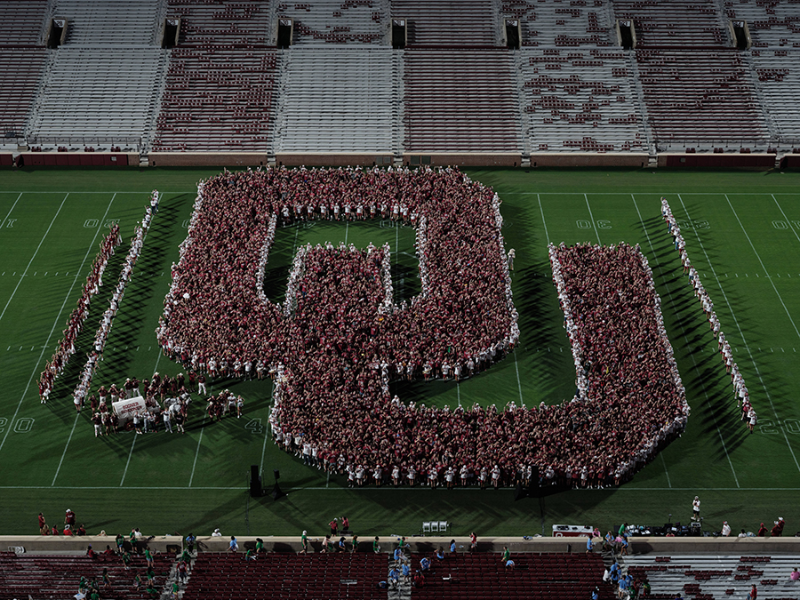 Class of 2030 posing together in a shape of an OU on the field