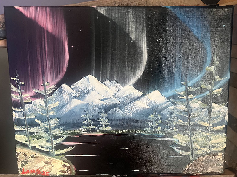 Red, white, and blue auroras dance in the sky over a snowy mountain range.
