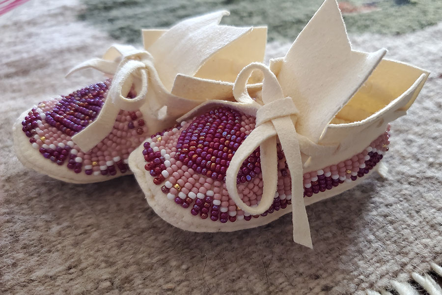Cream color moccasins beaded with pink, white, and purple beads in a heart pattern.