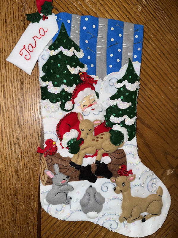 A quilted stocking showing Santa framed by woodland creatures.
