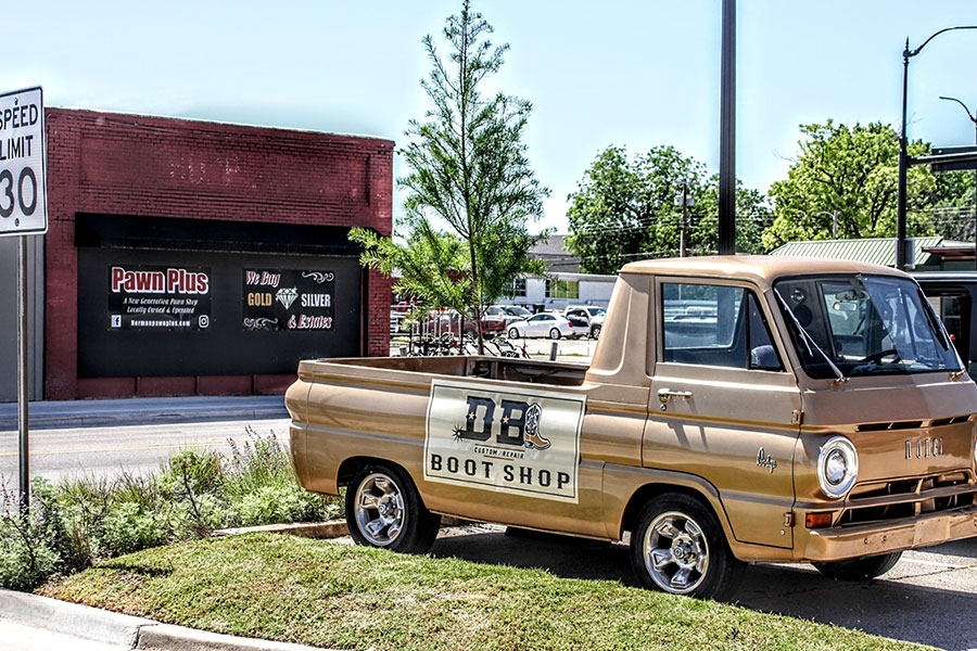 A photo of a vintage golden truck framed by a brick building.