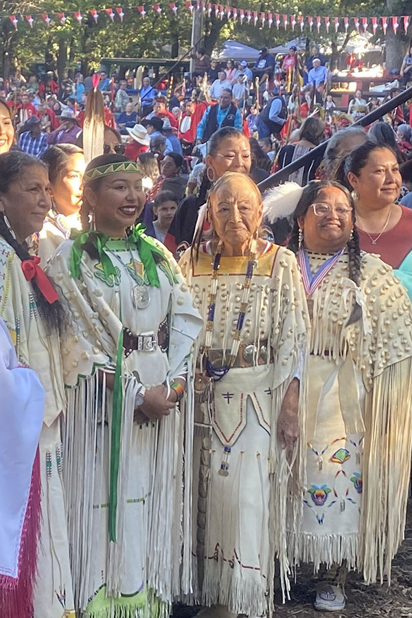 A photograph showing women in traditional dress with colorful beading.