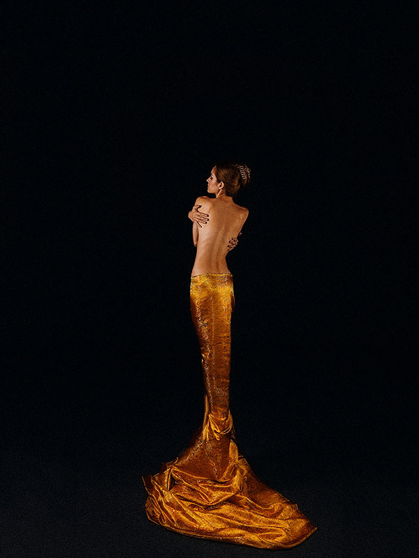 A female figure in a gold dress with a dripping train.