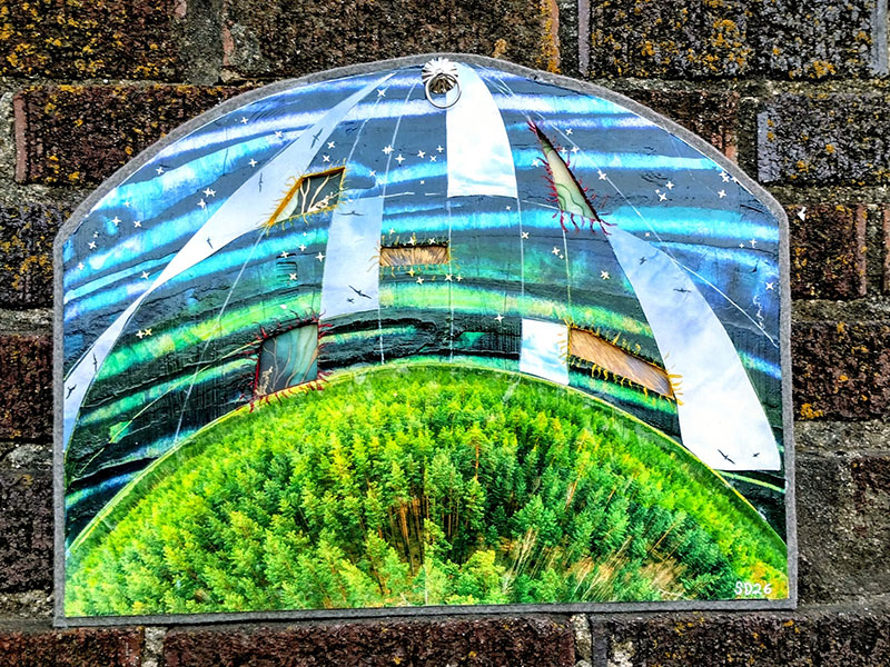 A collage of materials creating a dome of sky over a forest stitched together.