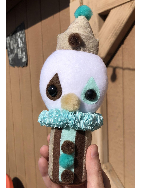 A handsewn clown of black, white, teal, and brown.