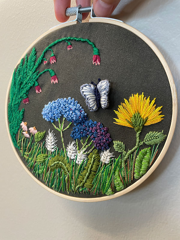 Embroidered flowers, a butterfly, and greenery.