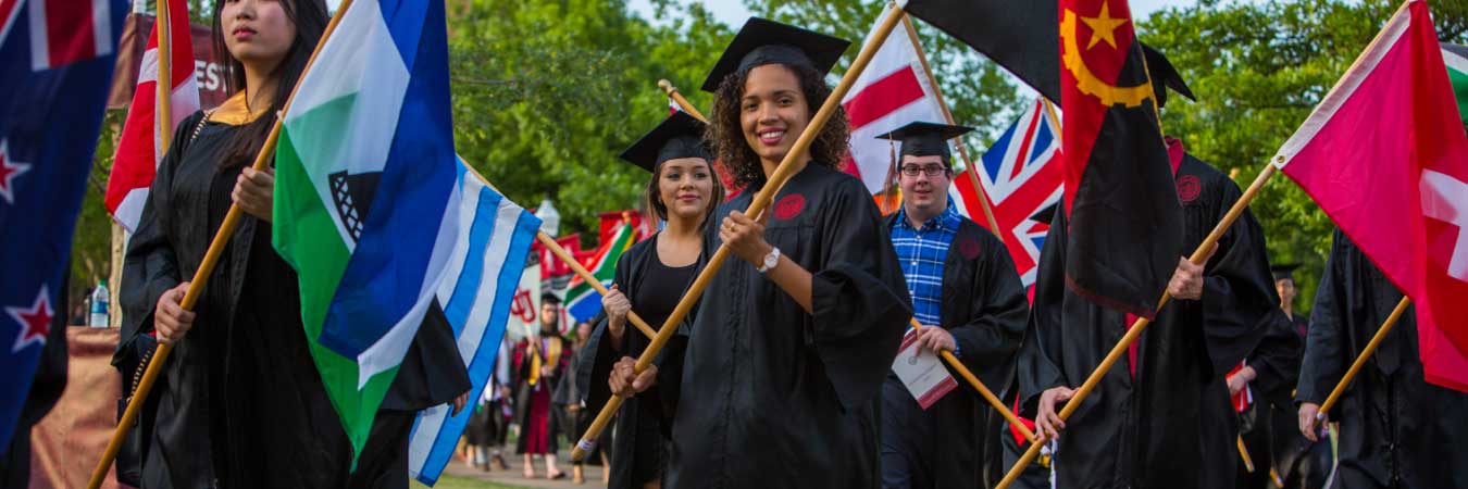 Students in Graduation Garb carrying multicolored flags