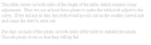 Text Box: This table curves on both sides of the length of the table, which requires some adjustment.&nbsp; Here we use at least three pleats to make the tablecloth adjust to the curve.&nbsp; If we did not do this, the cloth would pooch out on the smaller curved side and cause the skirt to stick out.
Put clips on each of the pleats on both sides of the table to stabilize the pleats.&nbsp; Smooth pleats down so that they will lay flat.
